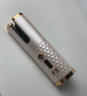 White portable automatic curling iron with a gold ceramic barrel and USB charging cable on a pink background.