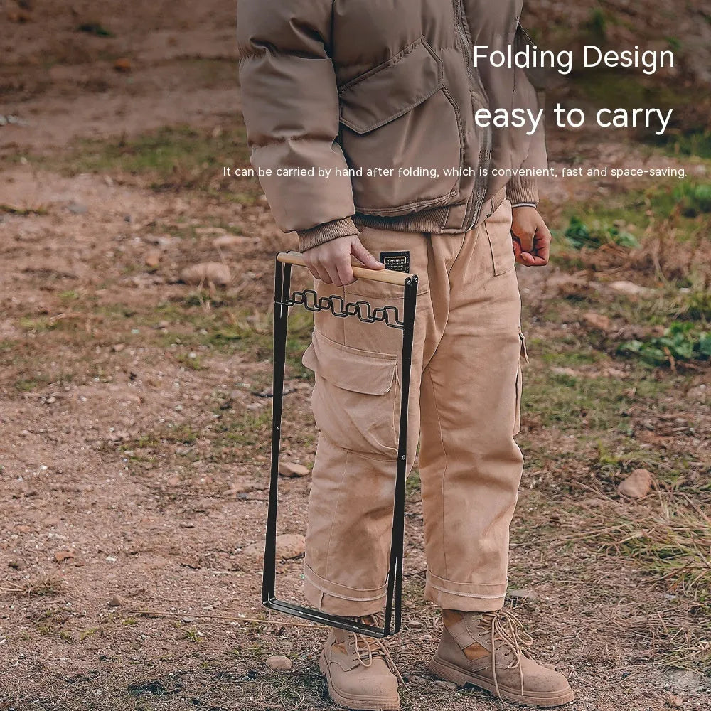 Black folding outdoor trash rack with a wooden handle, holding a rubbish sack.