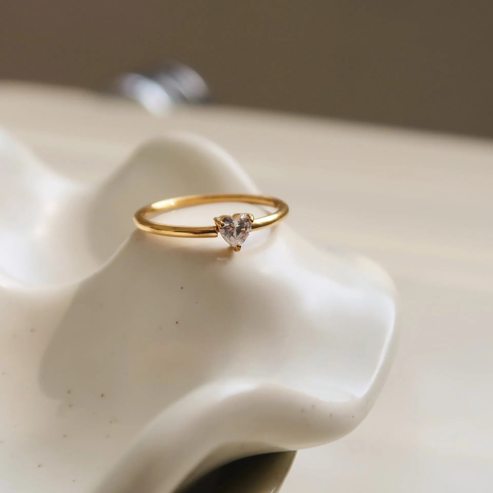 Golden electroplated stainless steel ring showing heart and oval shape designs on a hand.