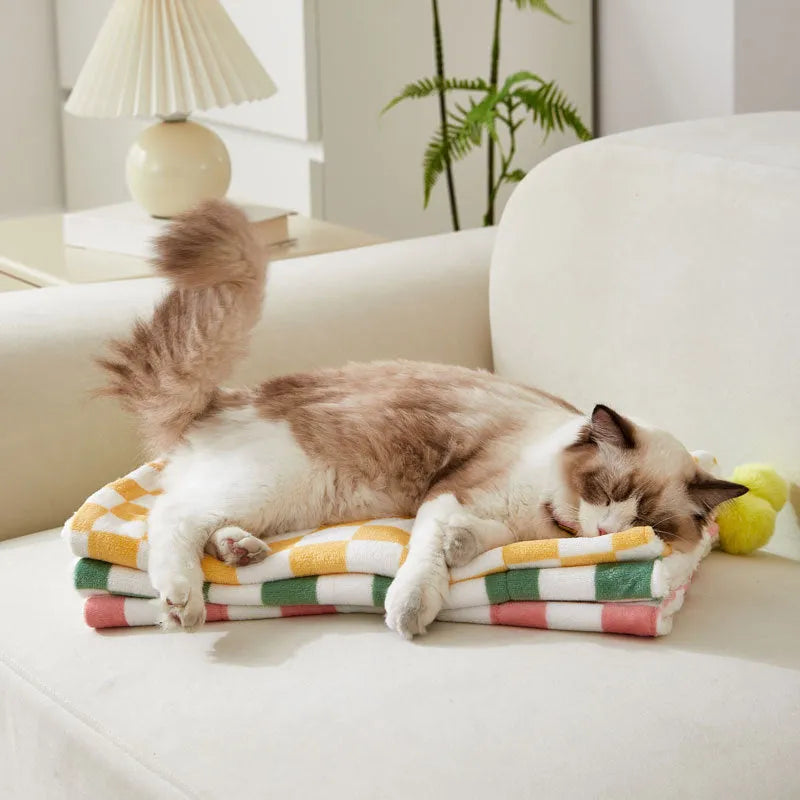 Green plaid pattern pet blanket with soft fleece texture on sofa