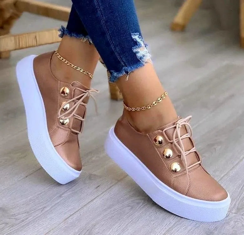 Women's white lace-up casual sneaker flats with silver rivet details on the round toe and low-top design.