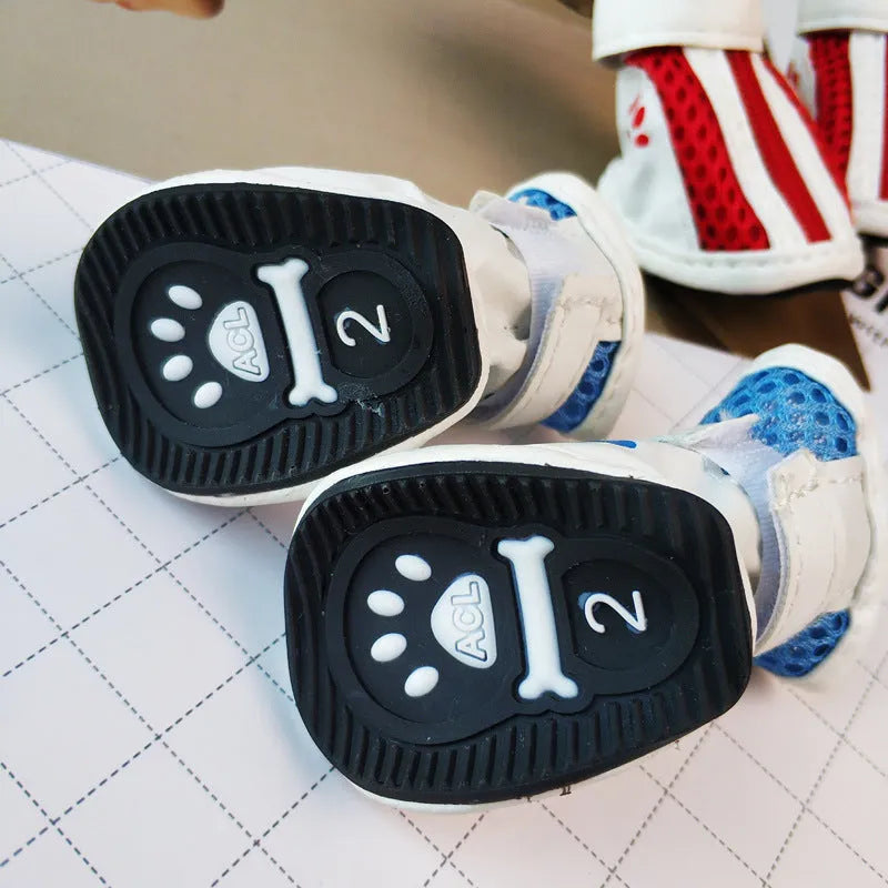 Four blue cloth dog shoes with zipper closures, showing non-slip soles, laid out on a white surface.