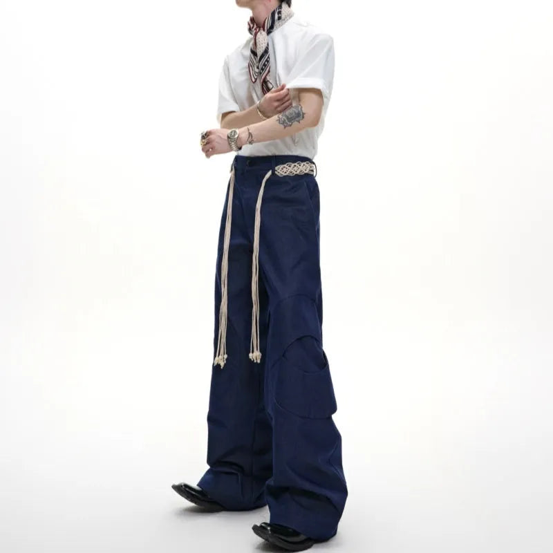 Men's dark blue straight-leg trousers showing heavy 3D cutting, belt stitching, and a front placket zipper.