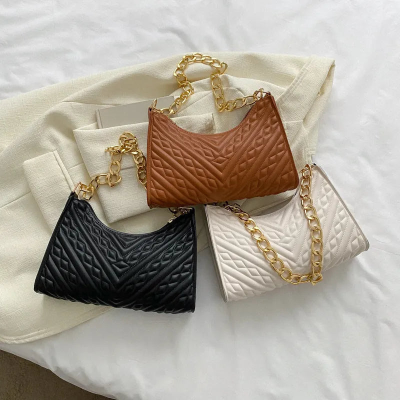 Vertical square brown PU shoulder bag with chain strap and soft handle on a table