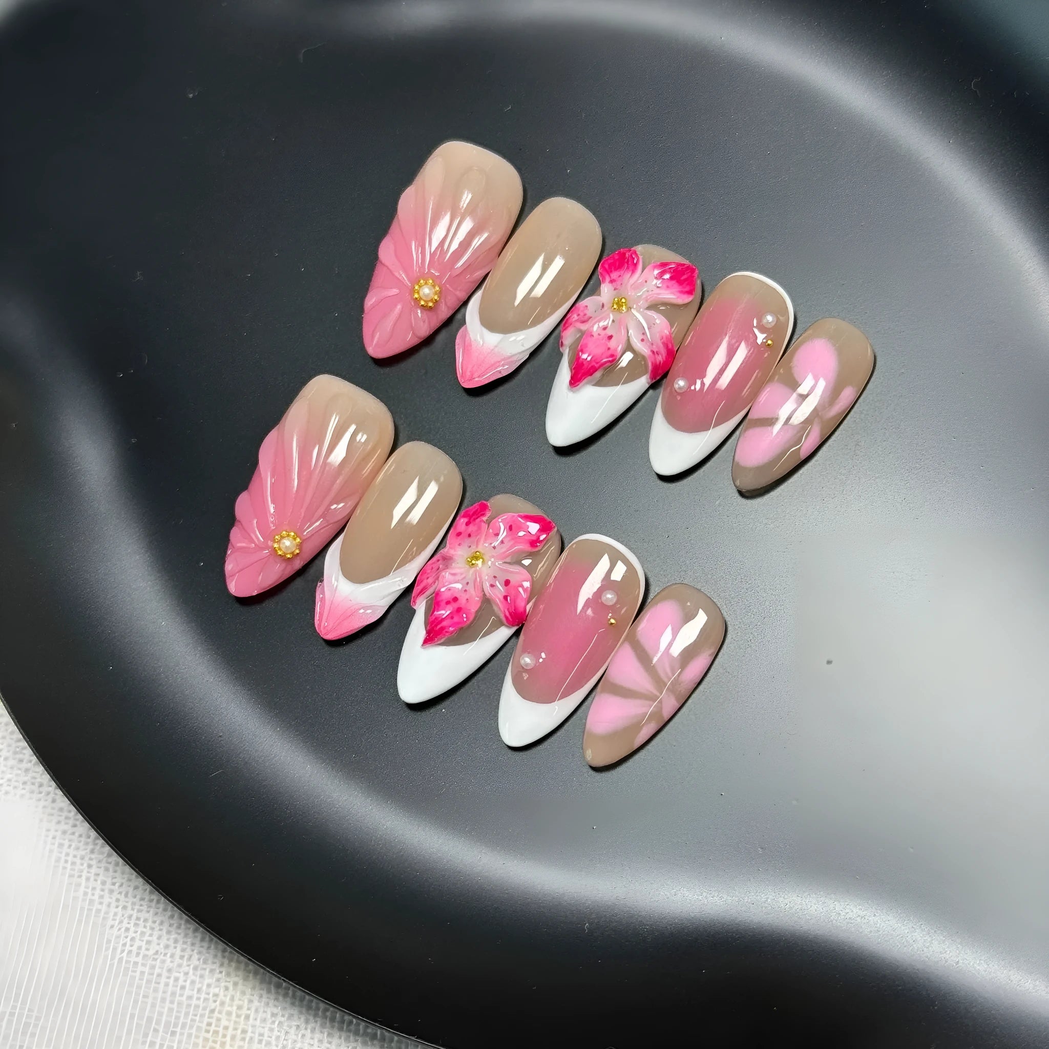 Set of French style artificial nails with white tips and 3D white lily flowers on almond-shaped plastic nail tips.