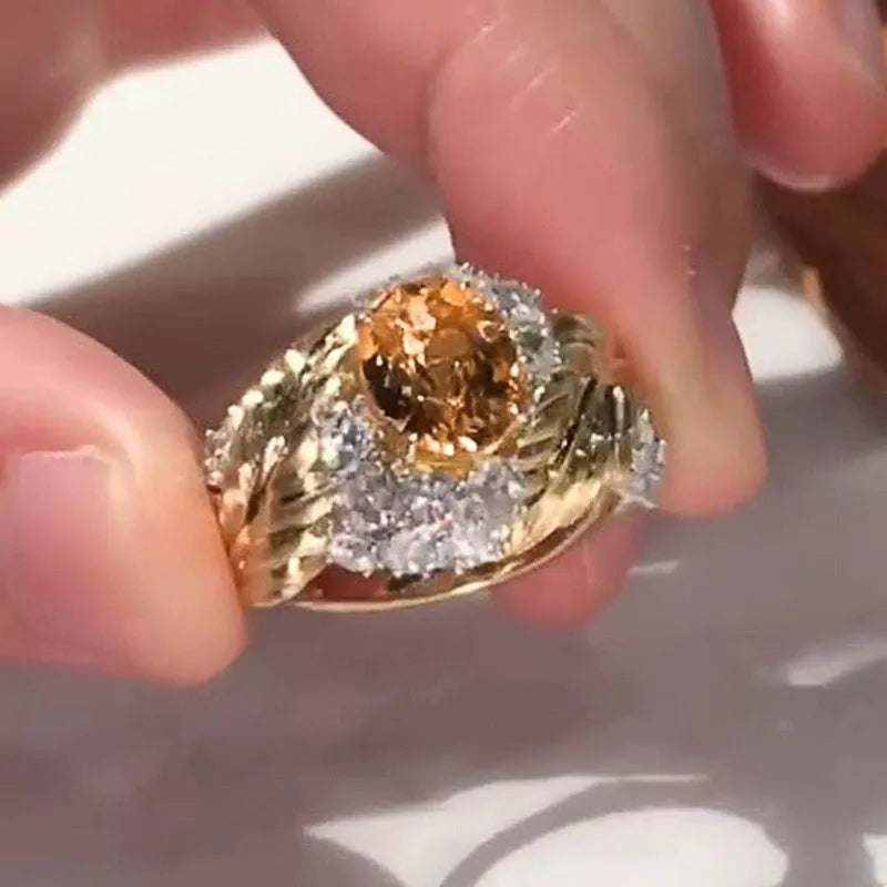 Gold-coloured copper ring with embossed feather design and yellow zircon stone inlay