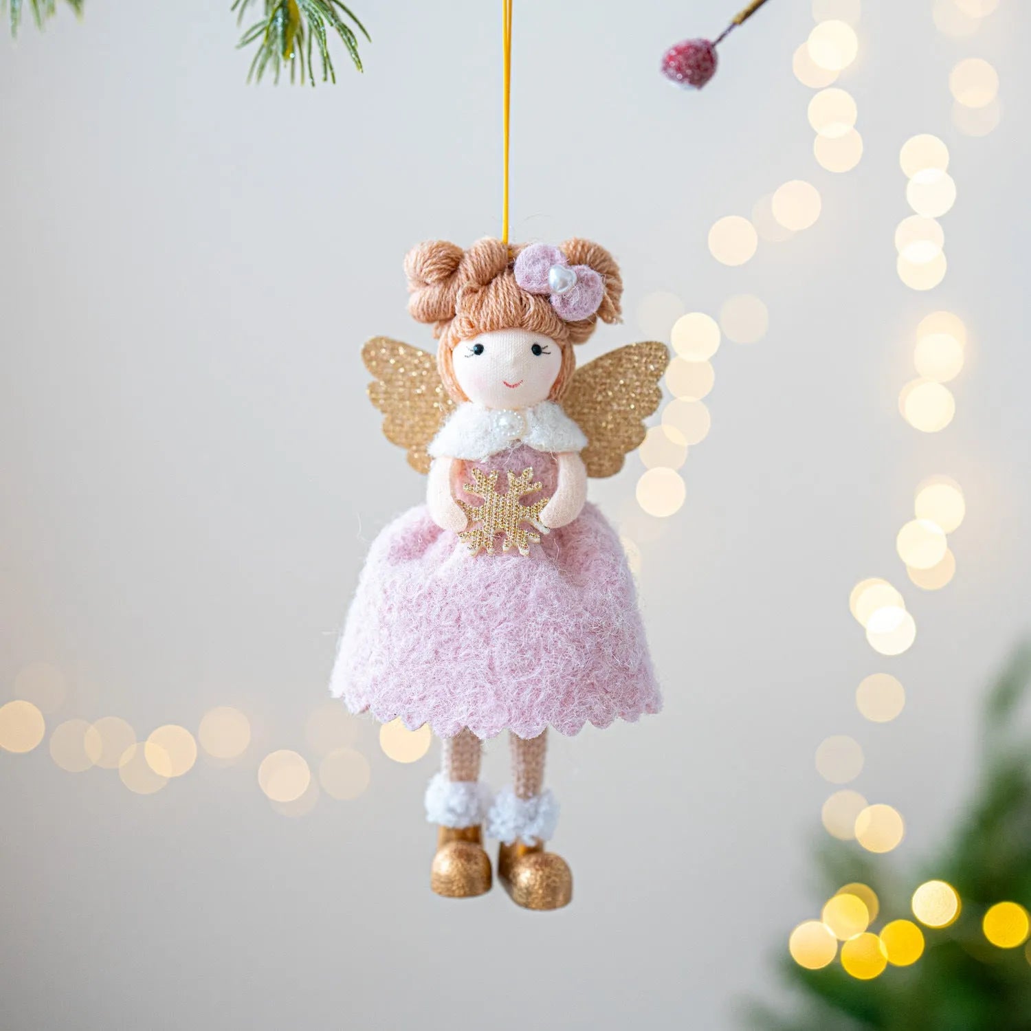 Pink and white cloth angel wings plush pendant Christmas ornament hanging against festive background
