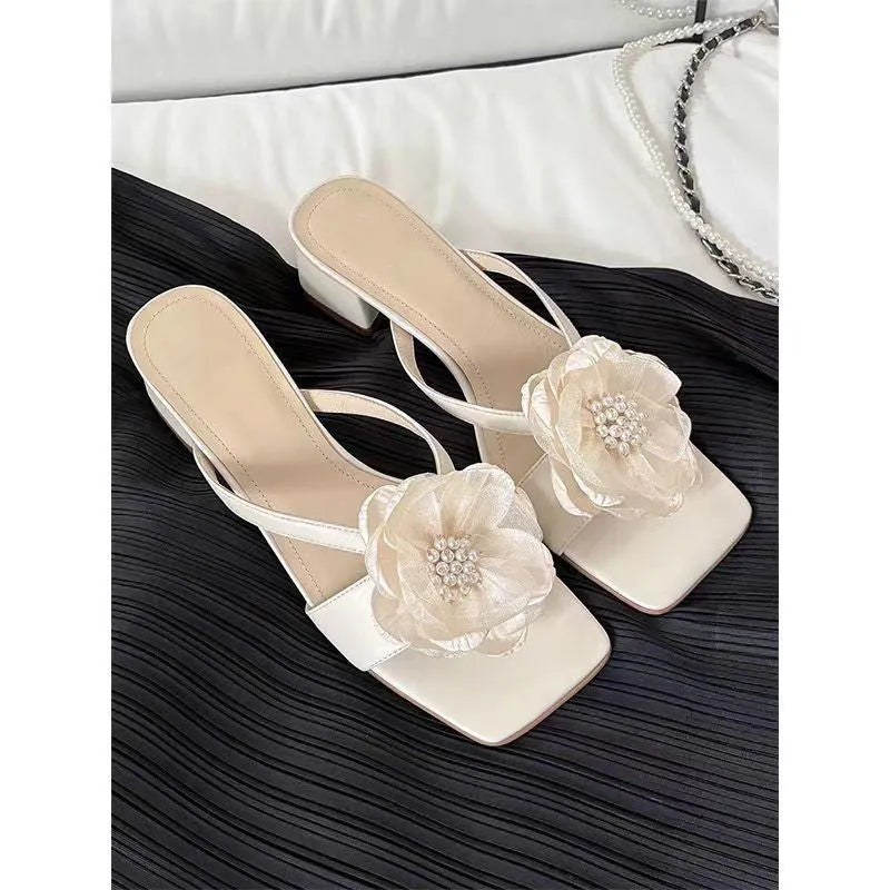 Women's cream-white satin sandals with a chunky heel and square toe on a light background.
