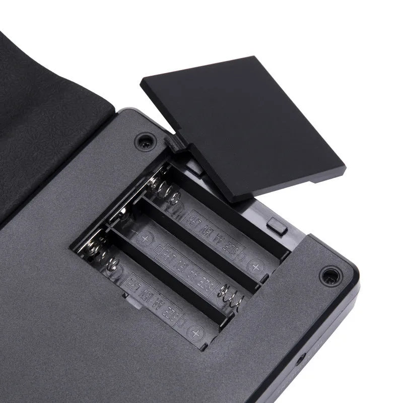 Rolled-up silicone keyboard next to black ABS control unit and speaker for portable 49-key electronic piano.