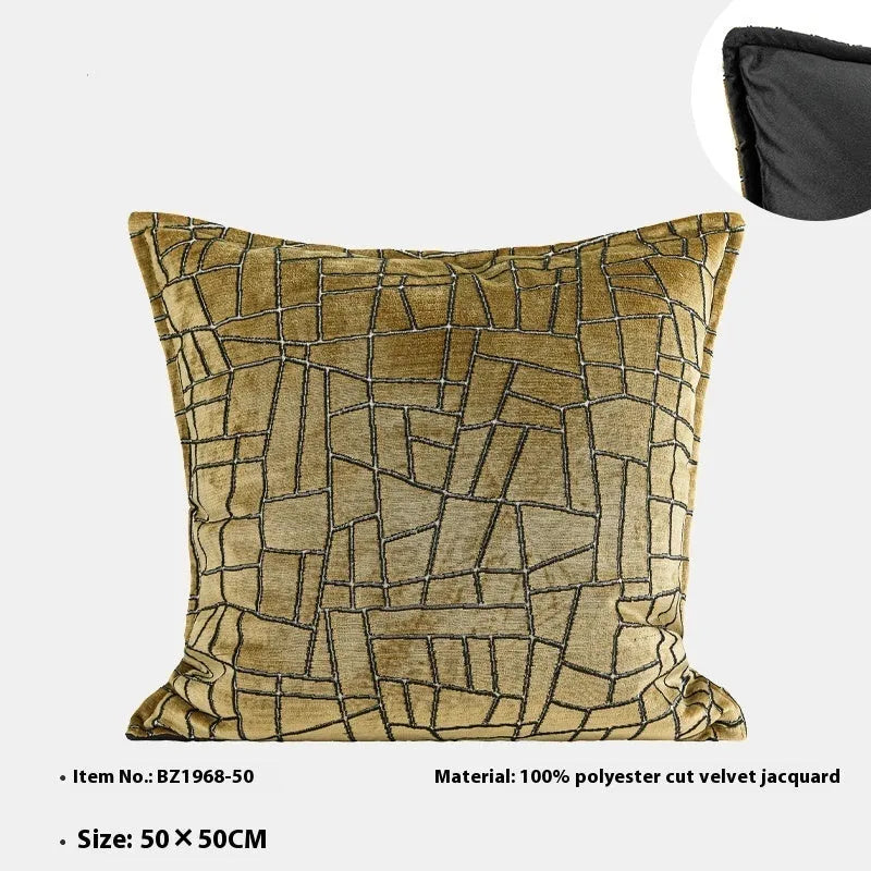 Gold geometric pattern on a velvet square cushion and a rectangular waist pillow against a sofa.