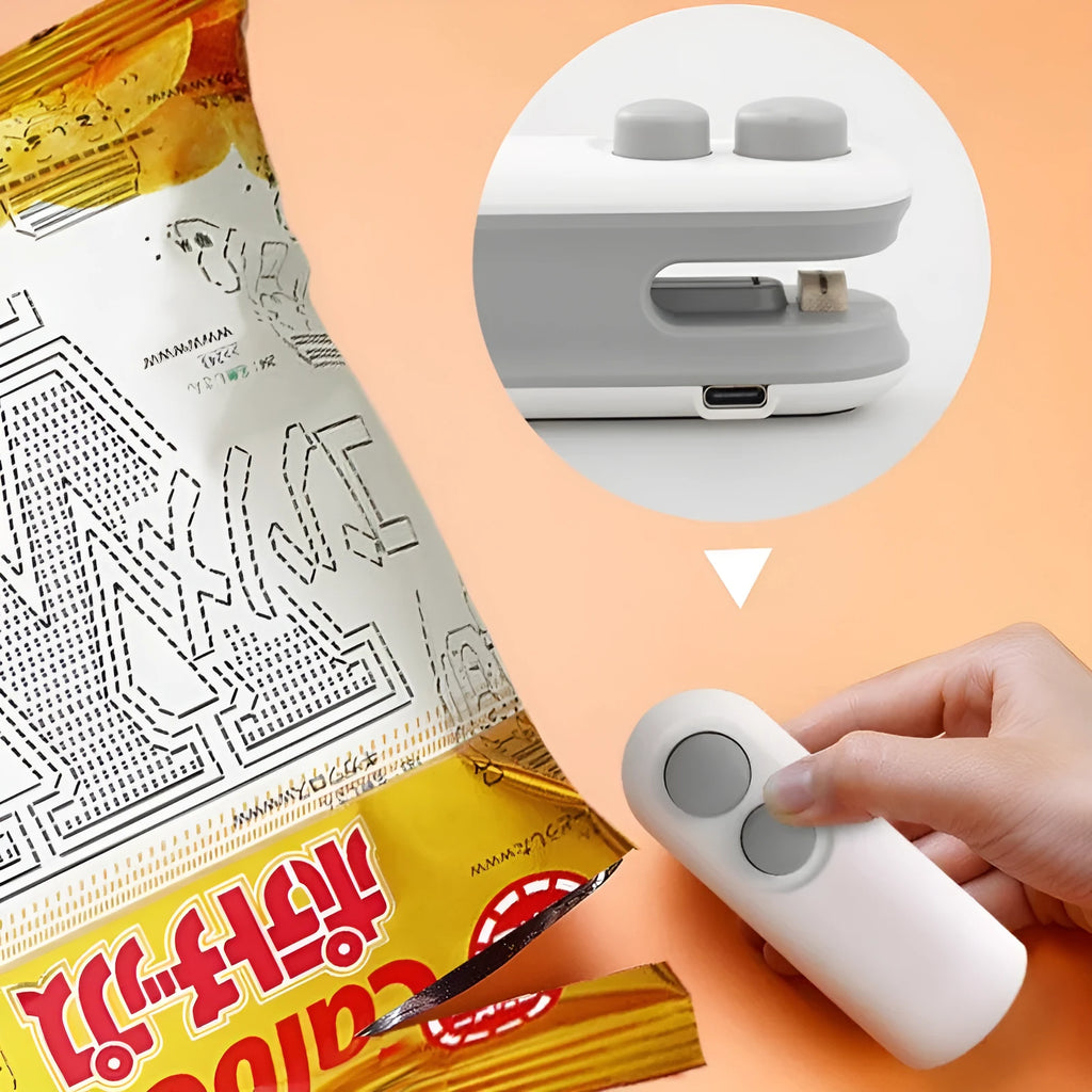 White handheld vacuum sealing machine with USB port and cutter blade on a kitchen counter.