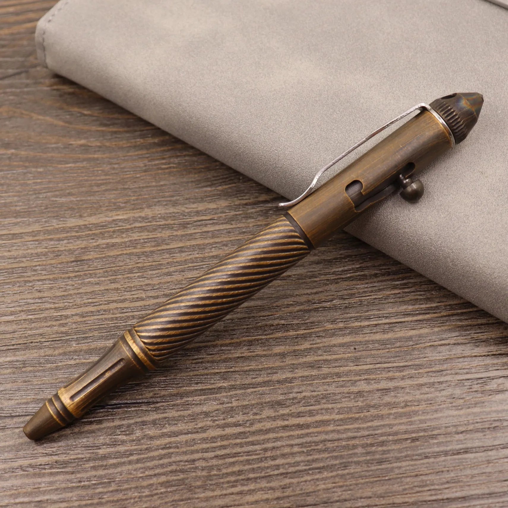 Brass bolt-action tactical pen in a retro copper finish, showing press mechanism and textured barrel.