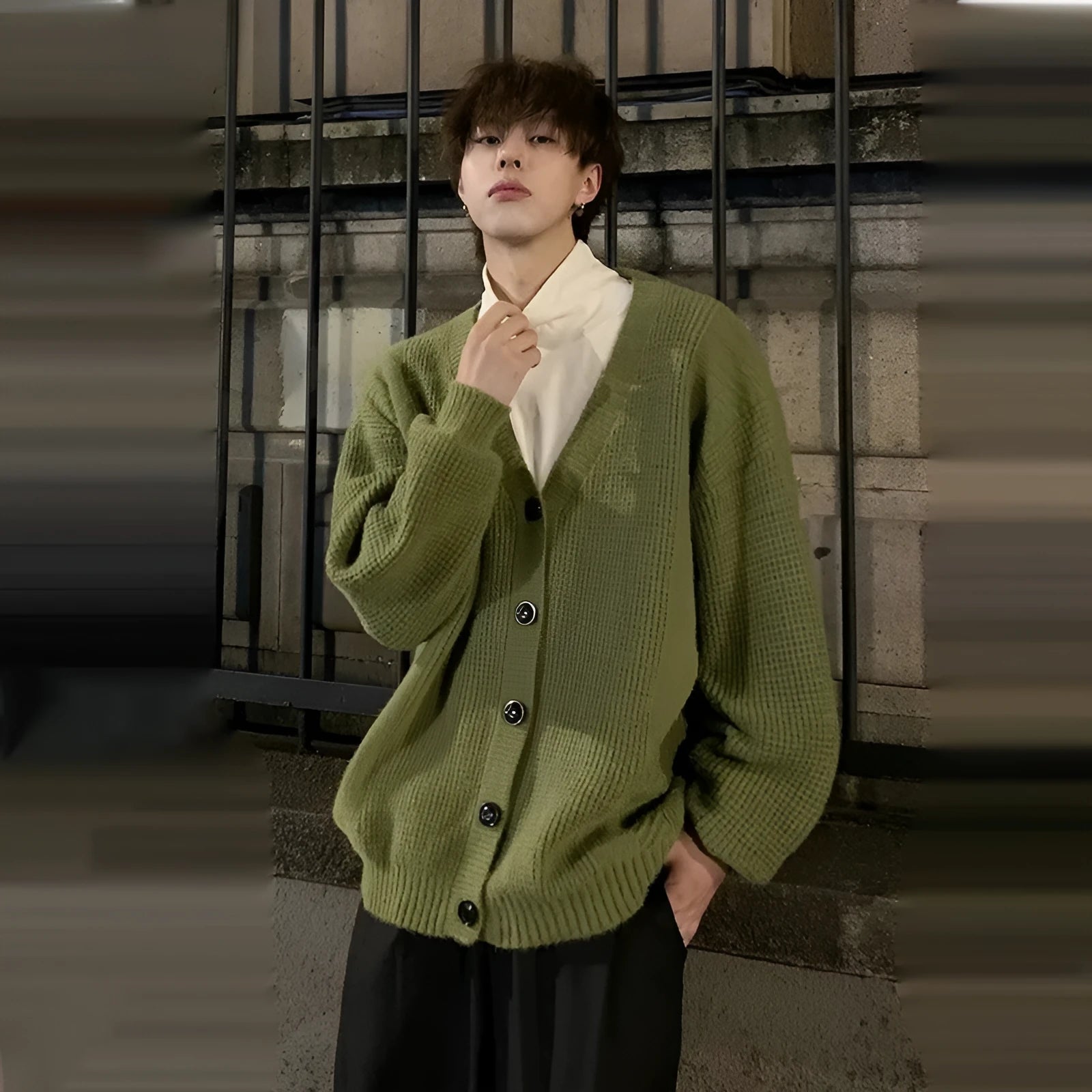 A man's loose-fitting V-neck knitted cardigan in a solid colour on a hanger.