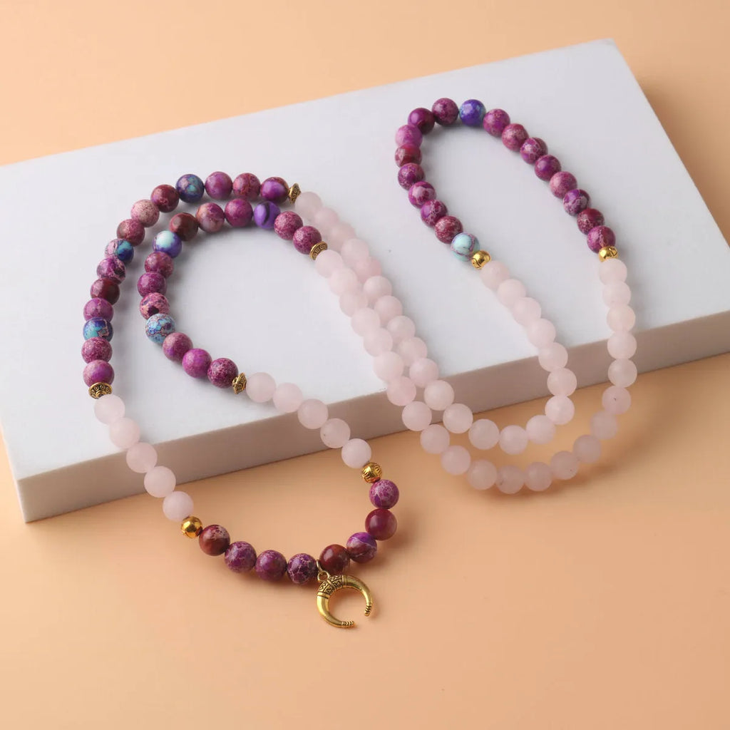 Round pink Emperor Stone pendant on a silver-tone chain, laid flat.