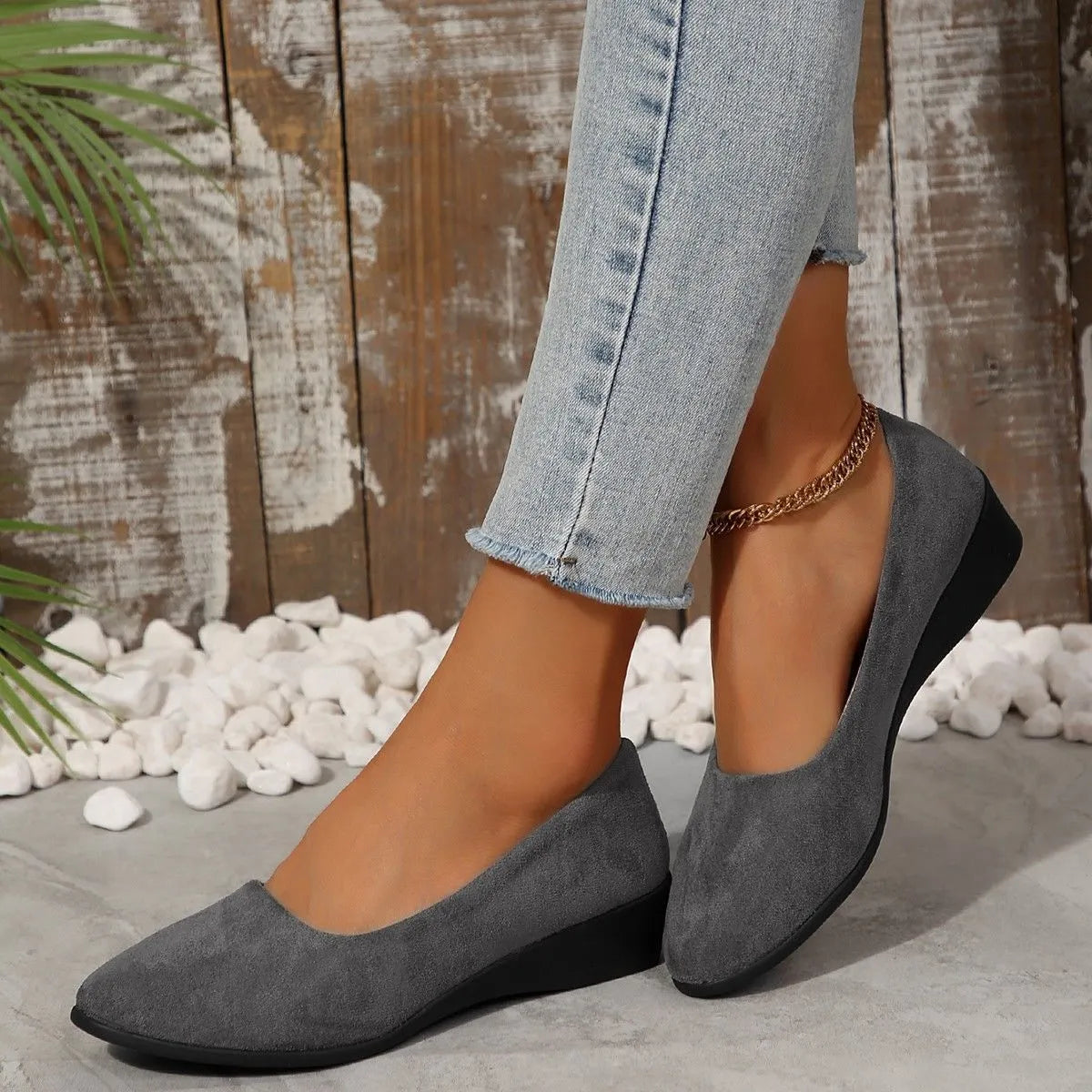 Women's black suede low wedge pumps with pointed toe and shallow mouth design on a rubber sole.