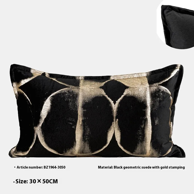 Black and gold abstract pattern decorative cushion with removable cover on a grey sofa.