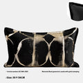 Black and gold abstract pattern decorative cushion with removable cover on a grey sofa.