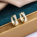 A pair of geometric drop earrings in 14K yellow, made from copper with zircon accents.