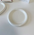 White porcelain round plate with chubby toot bear doodle pattern, shown as a plant saucer.