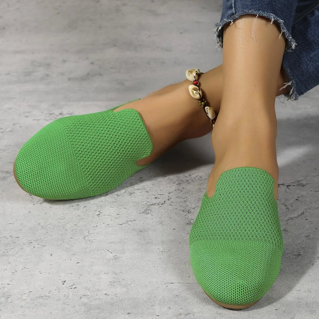 A pair of apricot-coloured mesh slip-on sandals with a cloth upper and flat rubber sole.