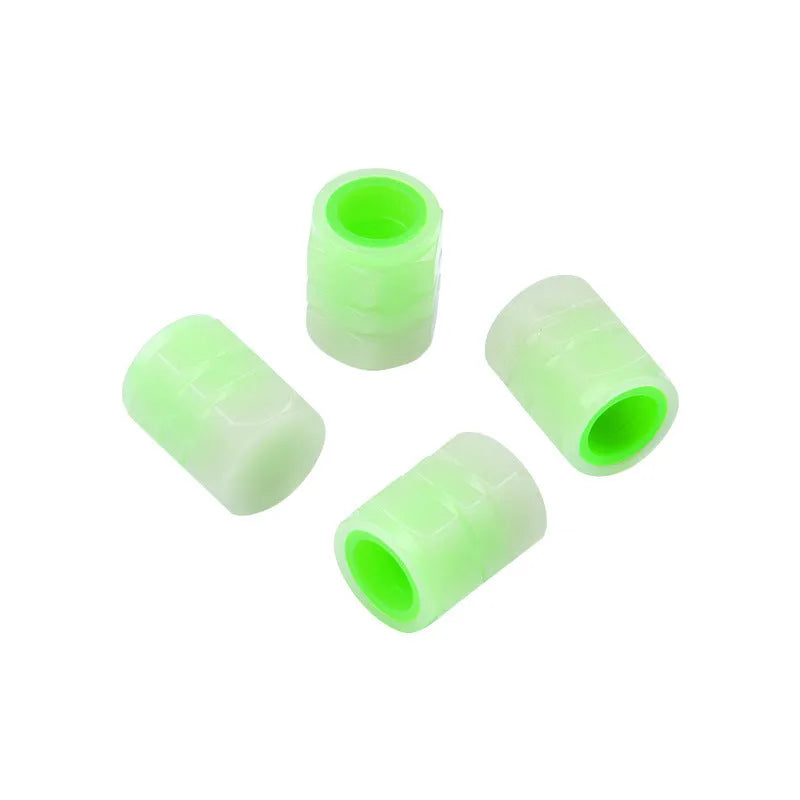 Set of four luminous rubber car valve caps glowing on a dark background.