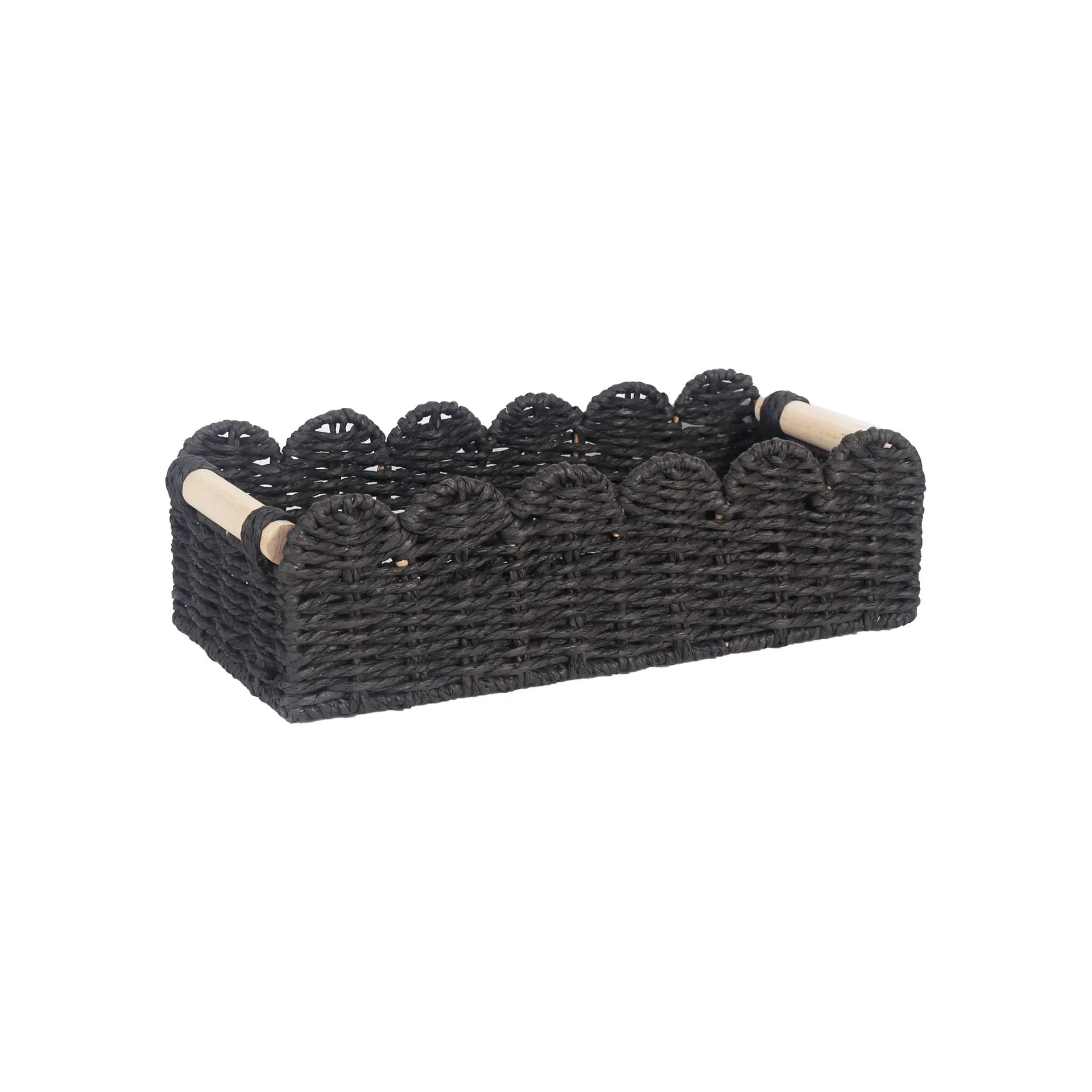 Modern woven paper storage basket in khaki colour on a wooden desktop, holding remote controls and pens.