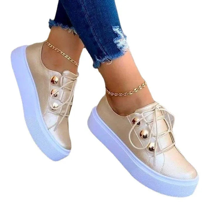 Women's white lace-up casual sneaker flats with silver rivet details on the round toe and low-top design.