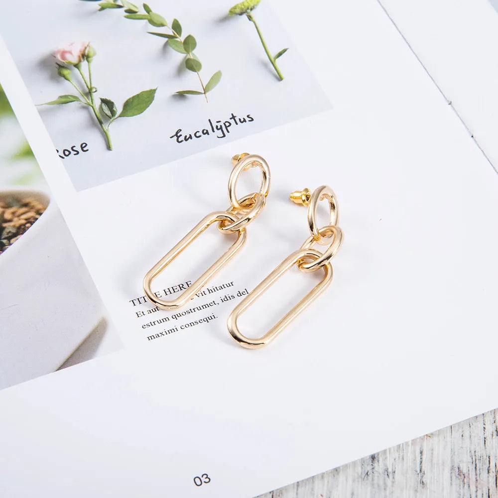 Geometric sterling silver needle hoop earrings with ring and line design on a white background.
