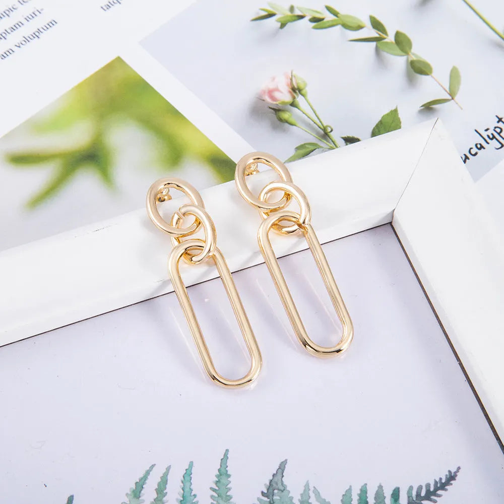 Geometric sterling silver needle hoop earrings with ring and line design on a white background.