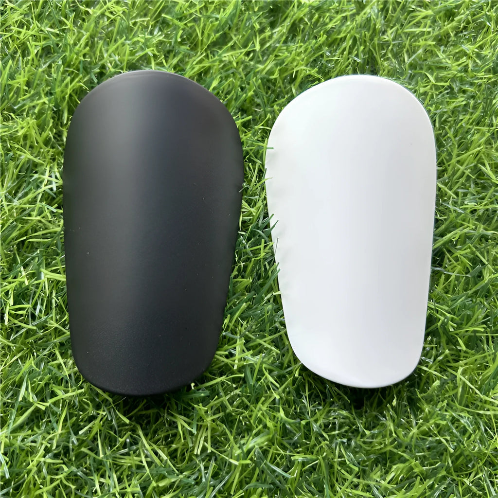 Pair of extra small black and white plastic football shin guards, size 8x5cm.