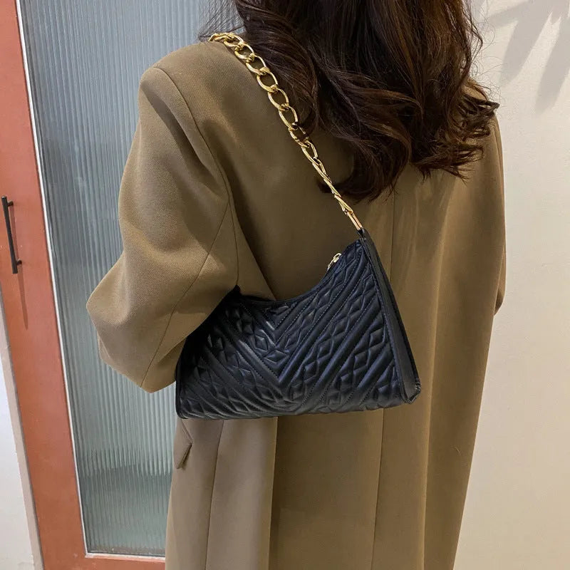 Vertical square brown PU shoulder bag with chain strap and soft handle on a table