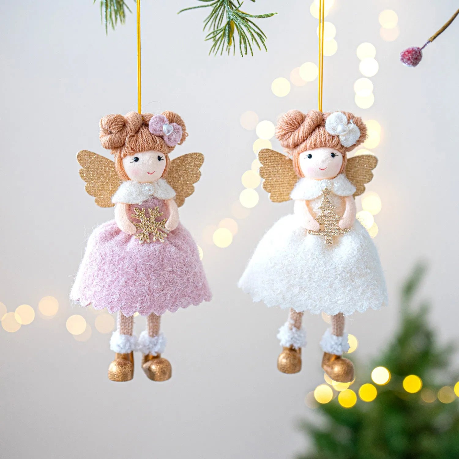 Pink and white cloth angel wings plush pendant Christmas ornament hanging against festive background