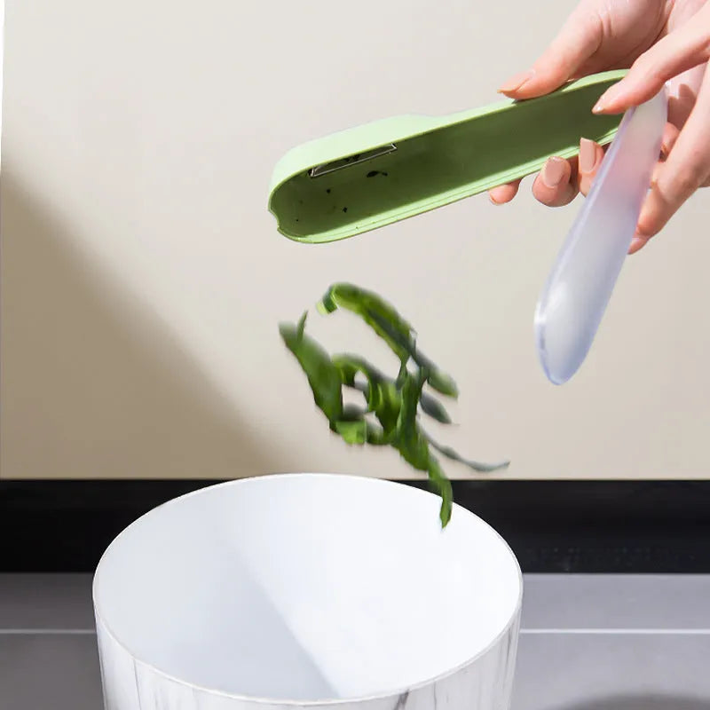 Dark green vegetable peeler with storage tube, showing stainless steel blade and hanging hole on handle.
