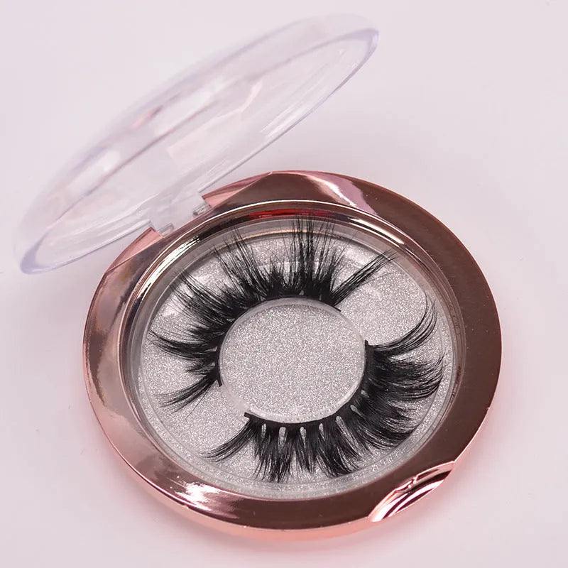 A pair of handcrafted 5D mink false eyelashes with applicator brush and storage case on a clean background.