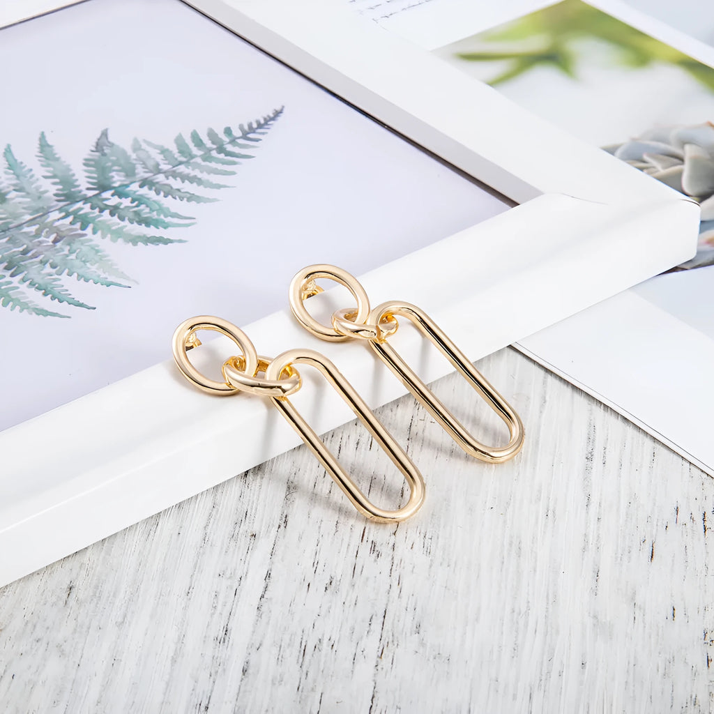 Geometric sterling silver needle hoop earrings with ring and line design on a white background.