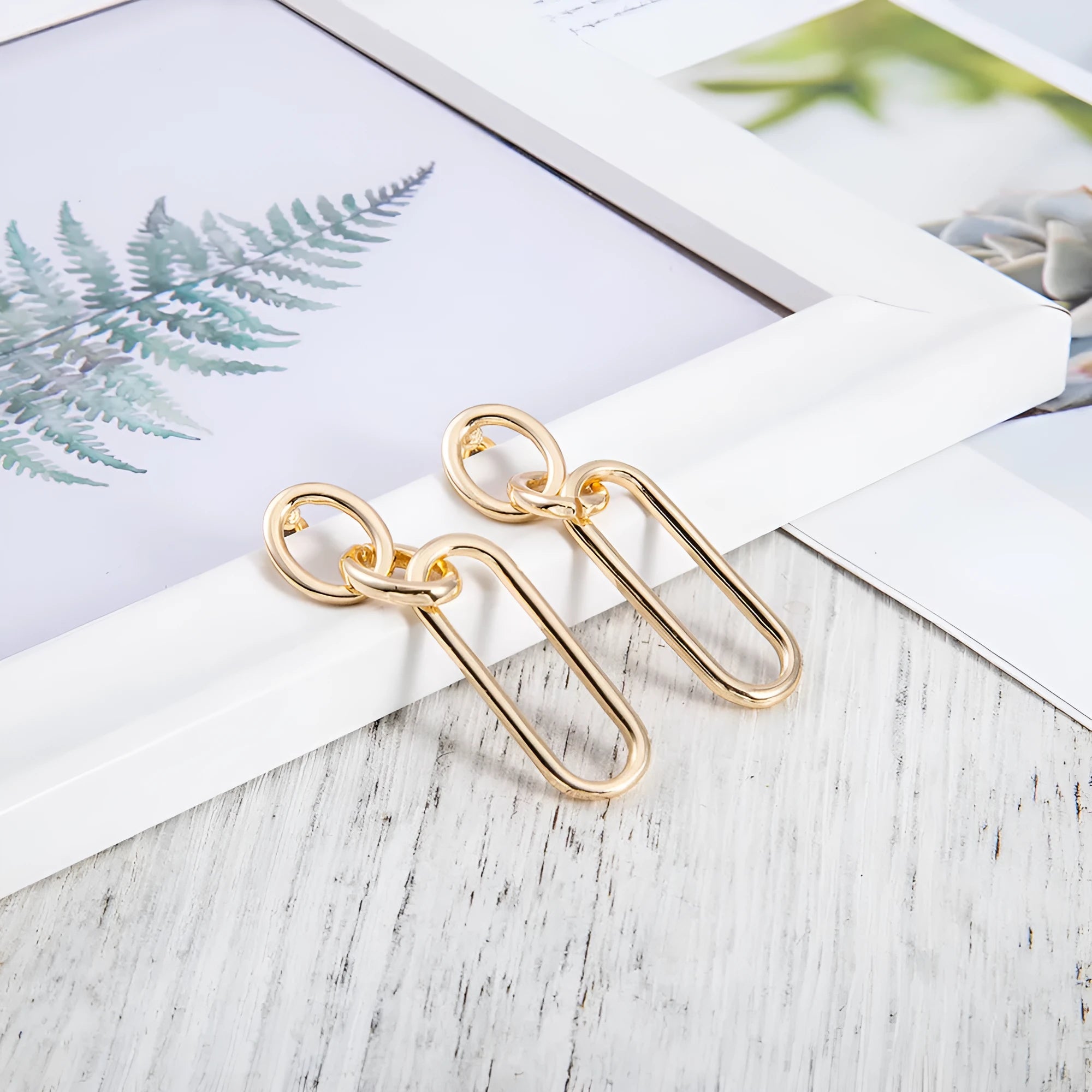 Geometric sterling silver needle hoop earrings with ring and line design on a white background.