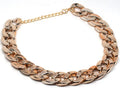 Gold geometric buckle dog chain collar on a small dog, showing twisted link design.