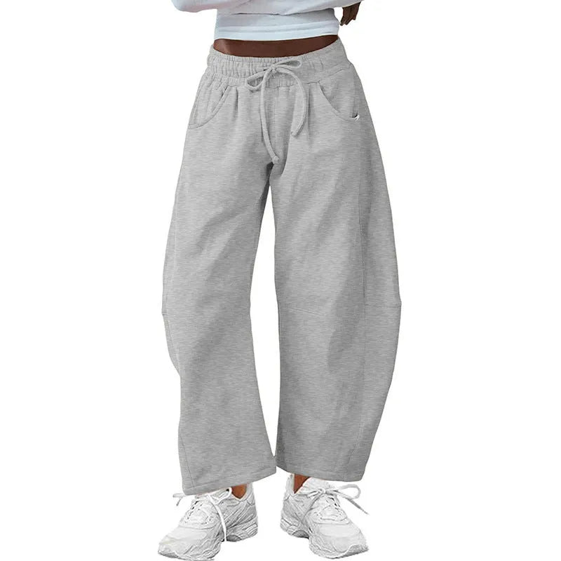 Women's loose grey cropped sweatpants with drawstring waist and side pockets on a hanger.