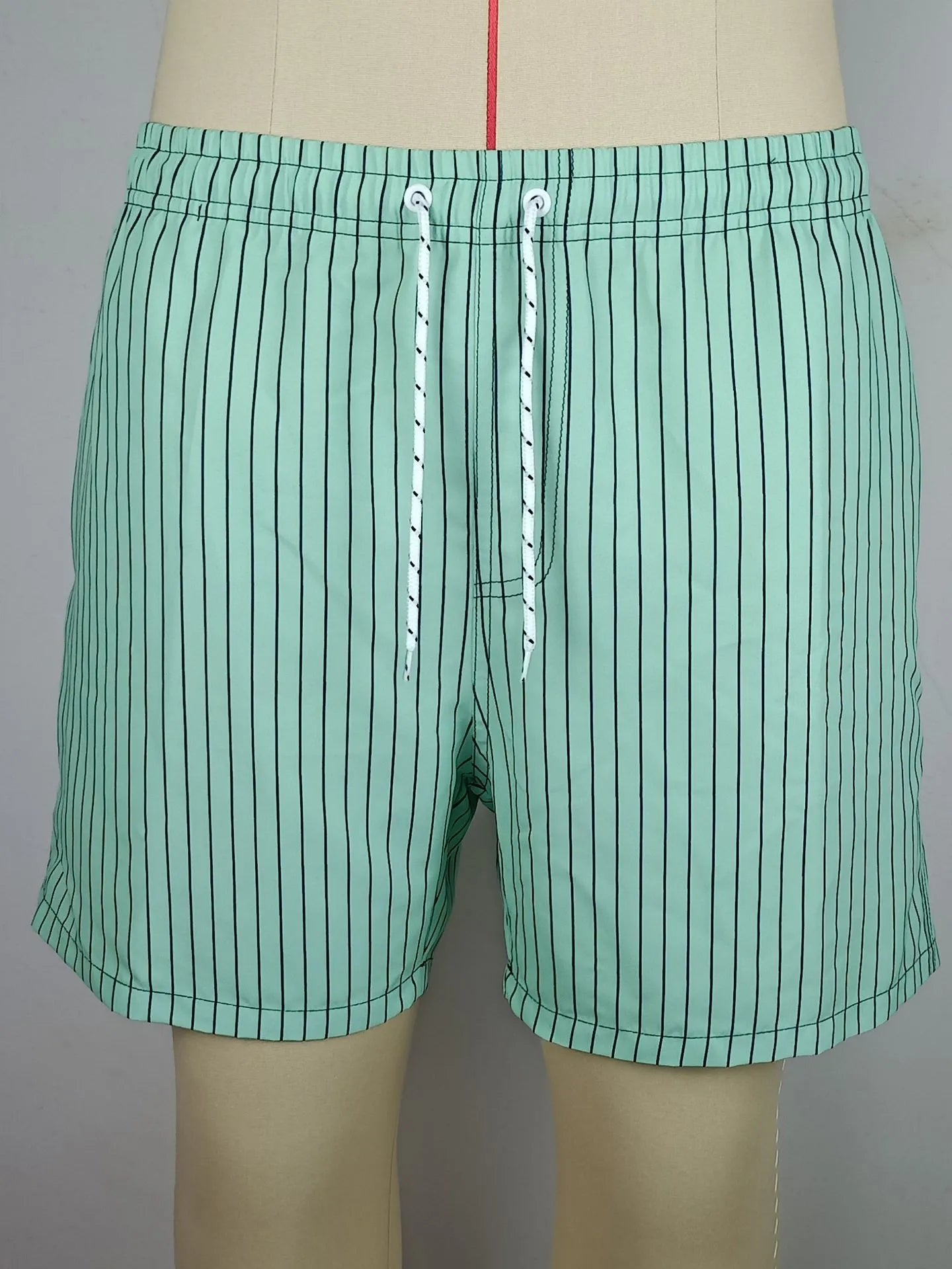 Navy blue and grey striped beach shorts with a straight leg opening on a mannequin.