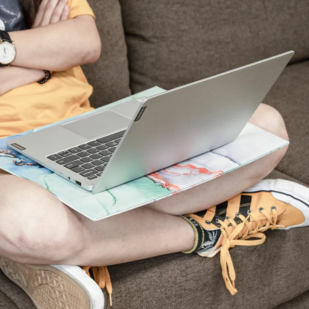 Heat-insulating laptop pad in black, gold, blue, and green colours on a desk