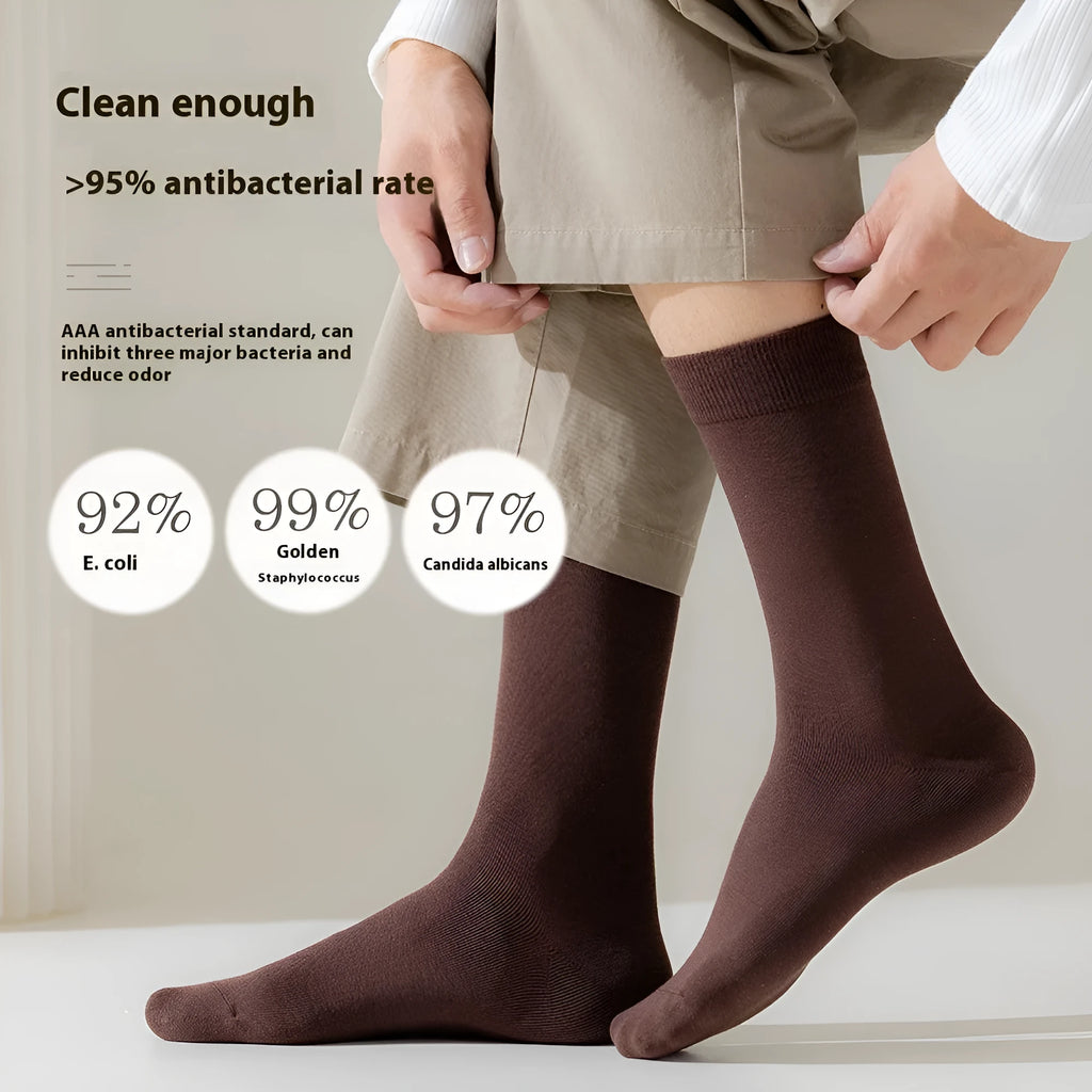 Men's solid colour mid-calf business socks made from combed cotton in various colours on a plain background.