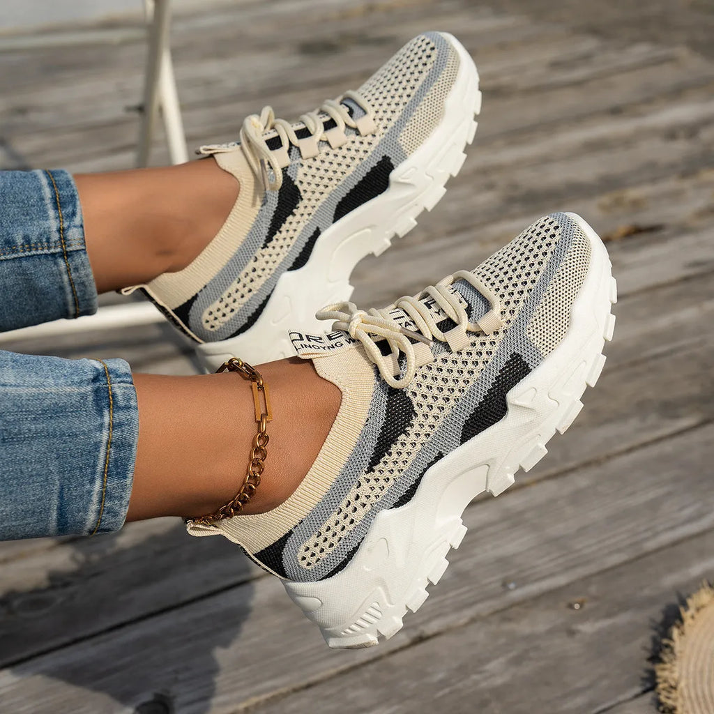 Women's Flyknit mesh sneakers in grey and white colour with flat rubber sole and lace-up front.