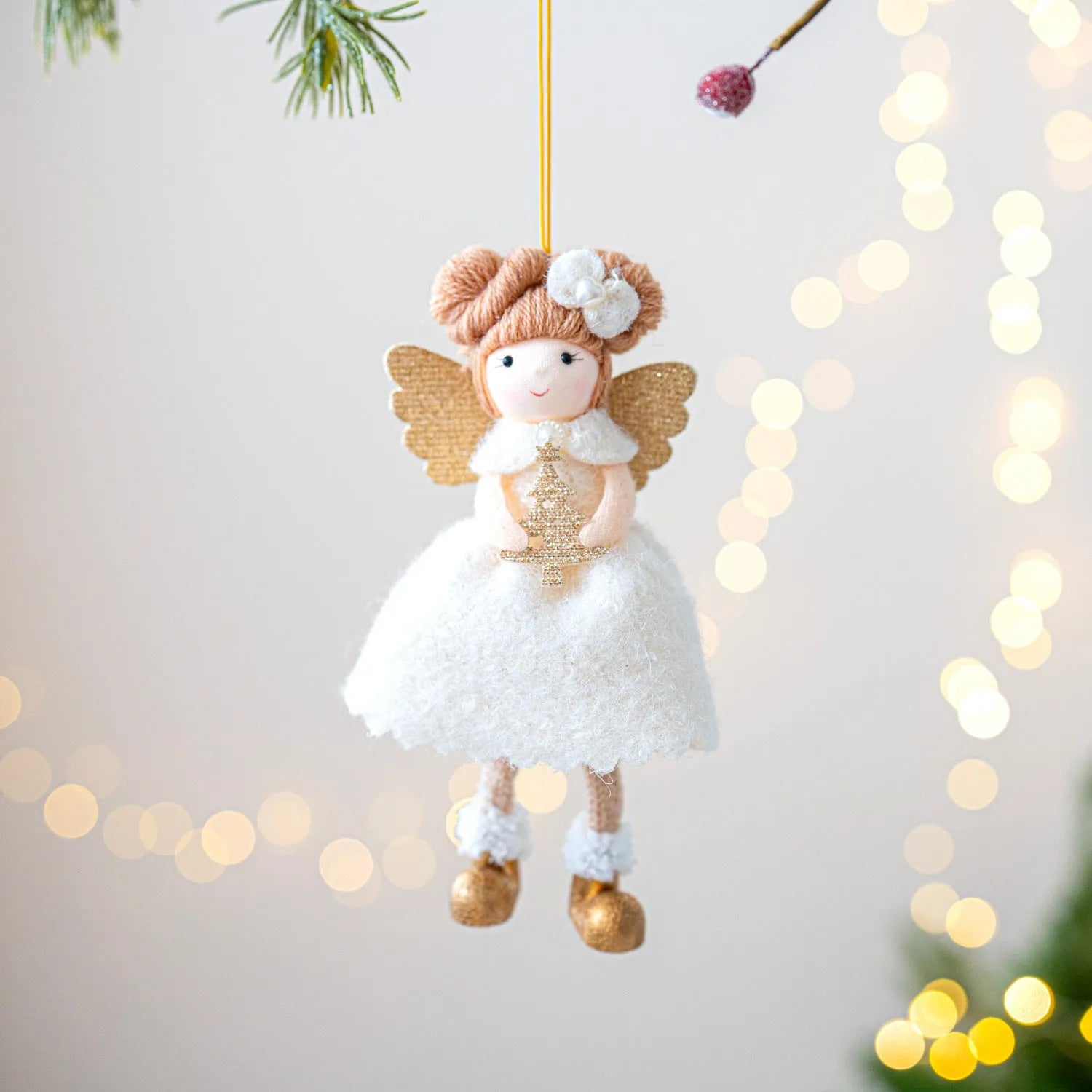 Pink and white cloth angel wings plush pendant Christmas ornament hanging against festive background