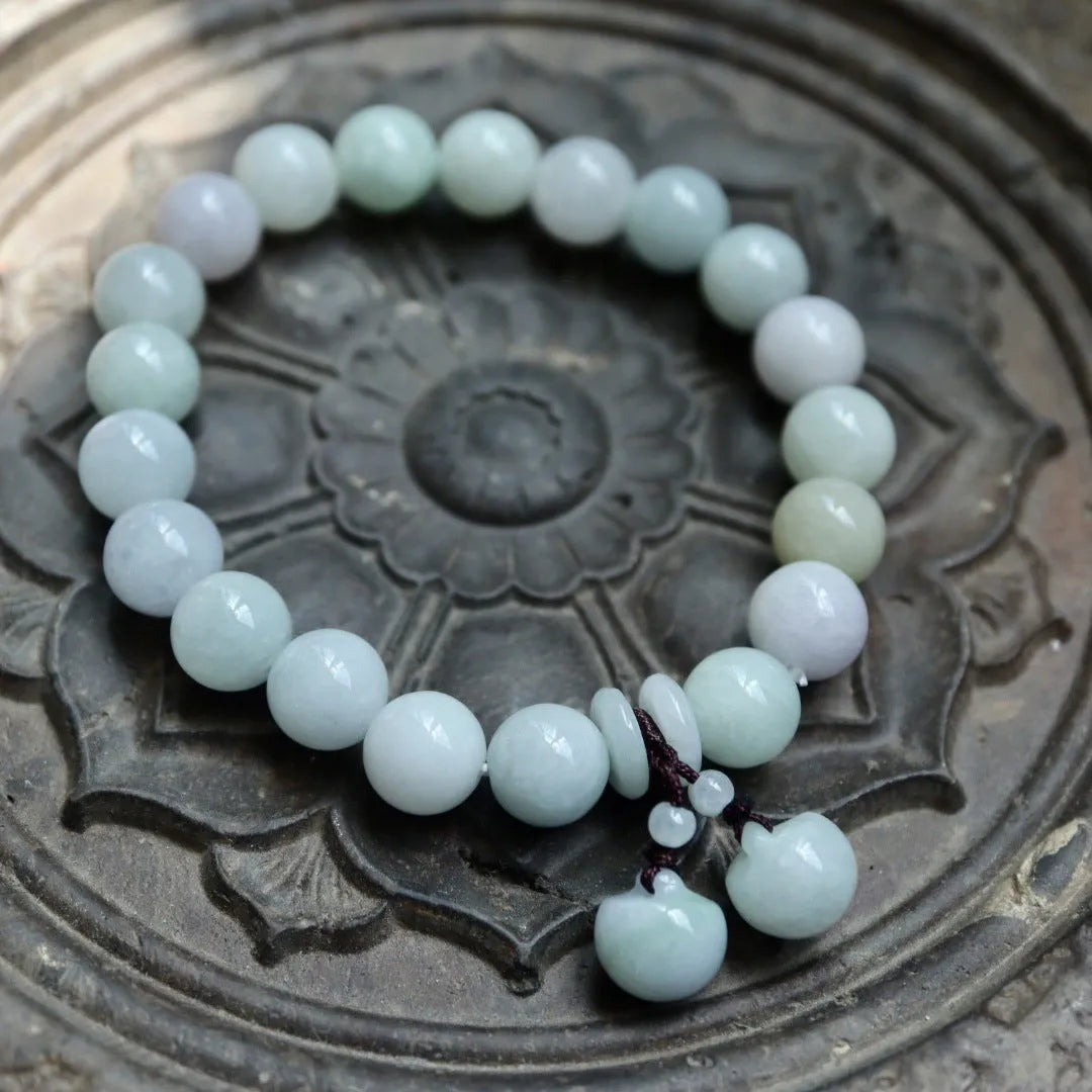 Emerald green jade bracelet with hanging symbolic charms including Maitreya Buddha design