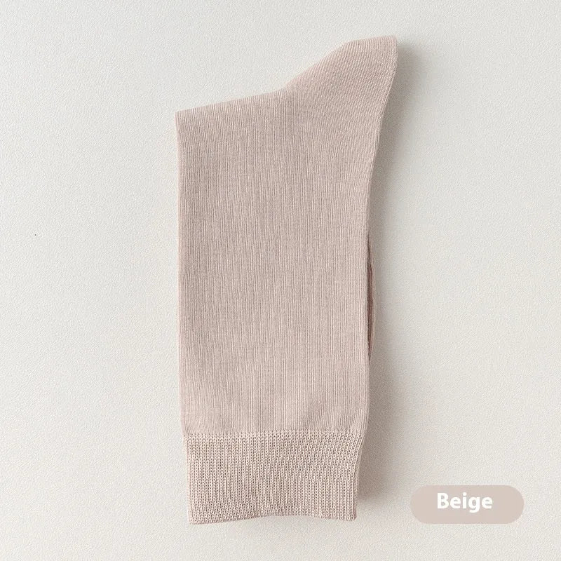 Men's solid colour mid-calf business socks made from combed cotton in various colours on a plain background.
