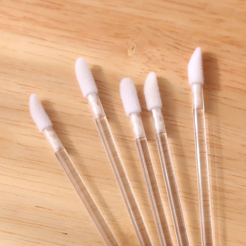 Pack of disposable lip brush applicators with flocked heads and black handles on a white background.
