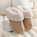 Women's brown plush indoor slippers with round toe, flat heel, and decorative stitching.