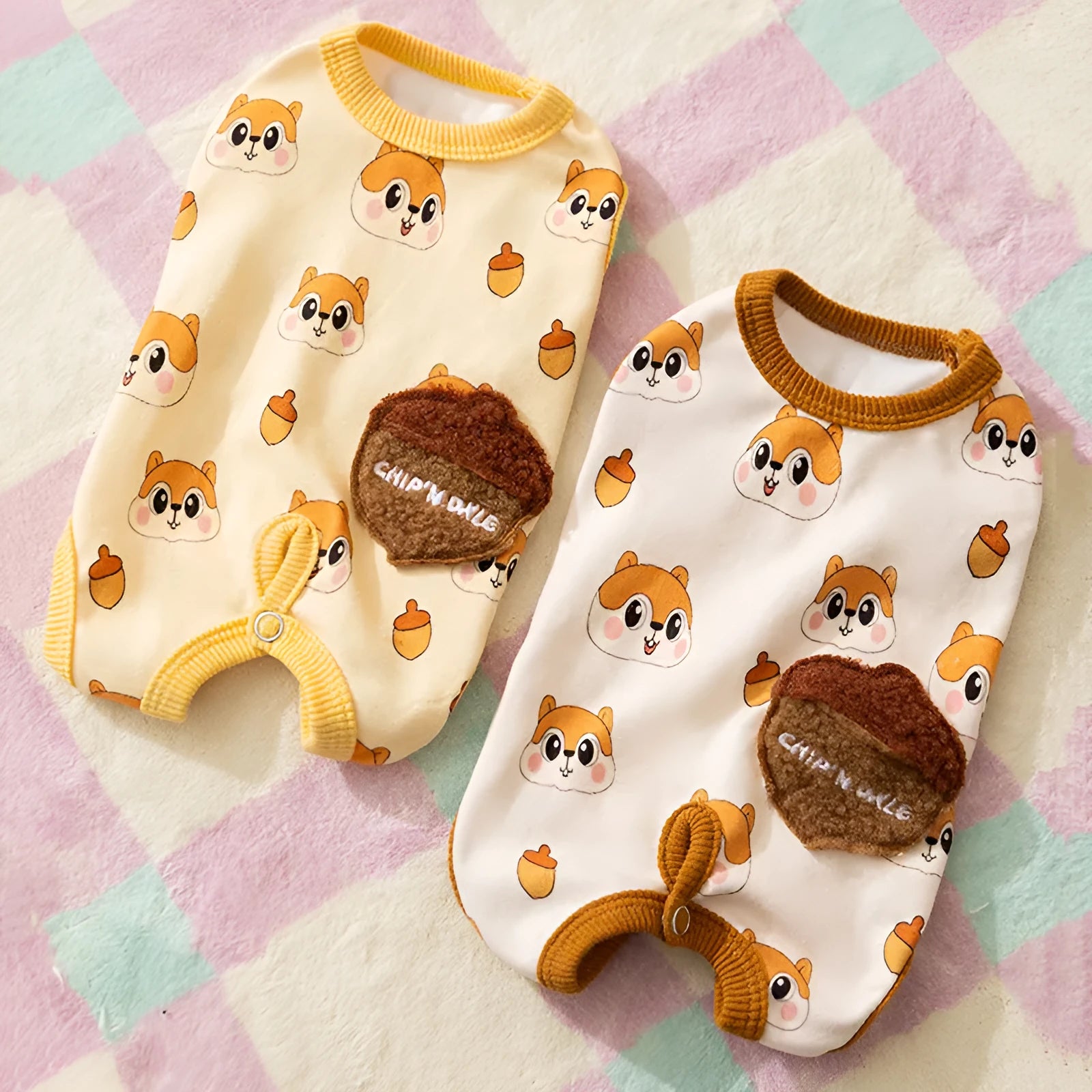 Small dog wearing Chip 'n' Dale themed cream onesie with yellow trim and embroidered acorn pocket