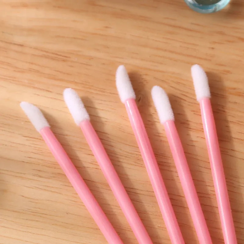 Pack of disposable lip brush applicators with flocked heads and black handles on a white background.