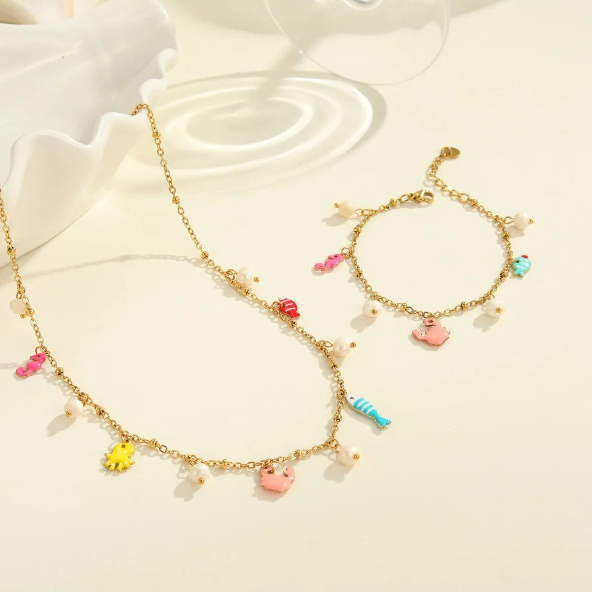 Stainless steel geometric pendant necklace with 18K gold electroplated chain and matching alloy bracelet on neutral background